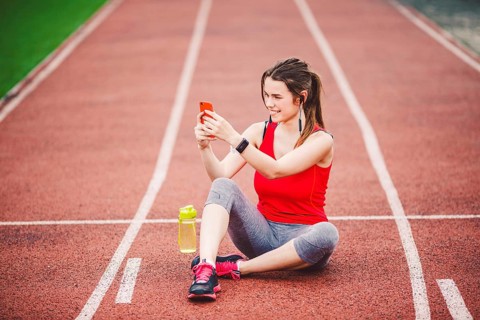Beautiful fitneß girl uses smartphone at stadium after workout. Sports and healthy. Sport woman use