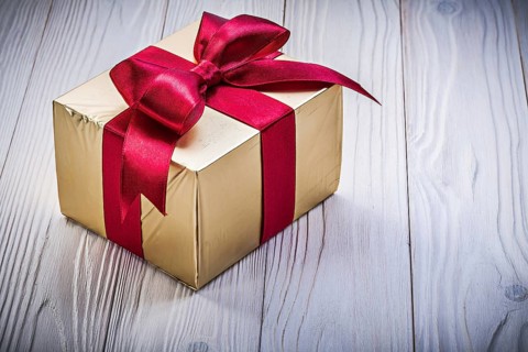 Present box in glittery paper on wooden board holidays concept