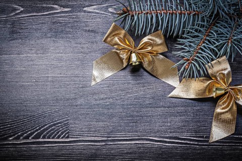 Goldish bows fir tree branch on wooden board holiday concept