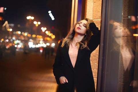 Portrait of Beautiful young woman in black on a background of a night city. night life
