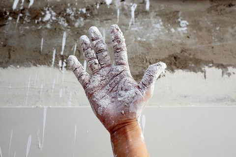 Astist plastering man hand with white dried cracked plaster texture in fingers