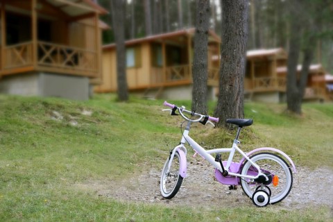 Chidren pink bicycle in wooden cabin mountain pine camping Pyrenees