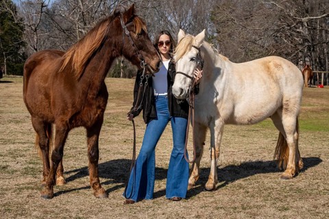 A beautiful brunette cowgirl poses with her horse before a ride in the countryside