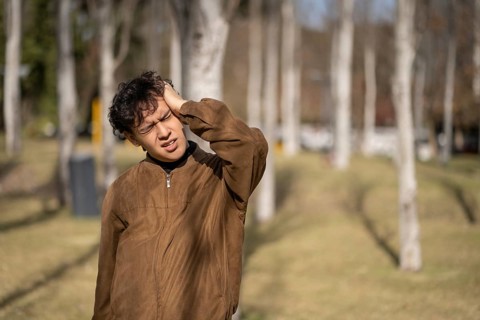 Stressed and tired young man touches his head because of a headache