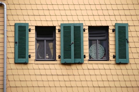 Open shutters on a striking façade of yellow shingles