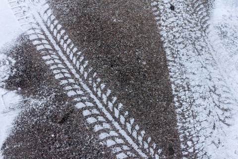 Tyre tracks on snow-covered asphalt, high-contrast texture in winter