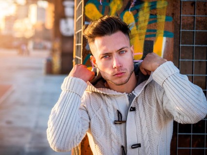 One handsome young man in urban setting in moden city, standing, wearing black coat and scarf in