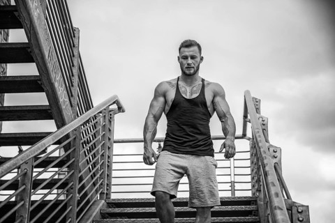 Handsome muscular man standing in city setting looking away to a side, walking down metal stairs