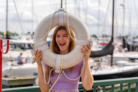 A gorgeous redhead model enjoys the perfect summer weather at a local marina, surrounded by boats