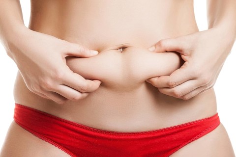 Overweight woman hand holding or pinching fat body belly paunch
