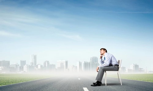 Young businessman sits on an office chair, thoughtful and looking up