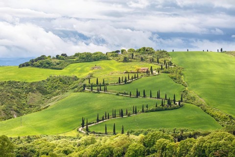 Tuscan rural landscape view with a winding road on a hill