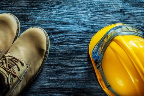 Safety boots building helmet goggles on vintage wooden board