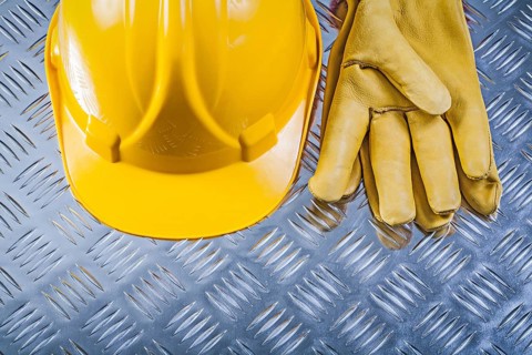 Protective leather gloves hard hat on corrugated metal background construction concept