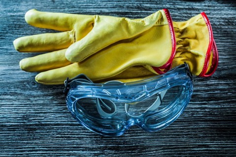 Protective leather gloves glasses on wooden board