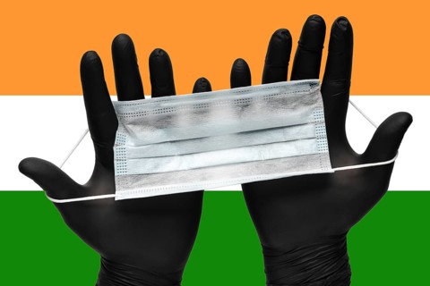 Doctor holds face mask in hands in black medical gloves on background colors National Flag of India