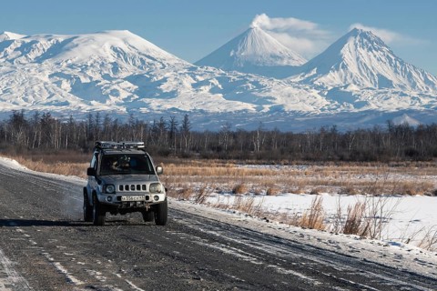Japanese Sport Utility Vehicle Suzuki Jimny driving along road on background beautiful winter