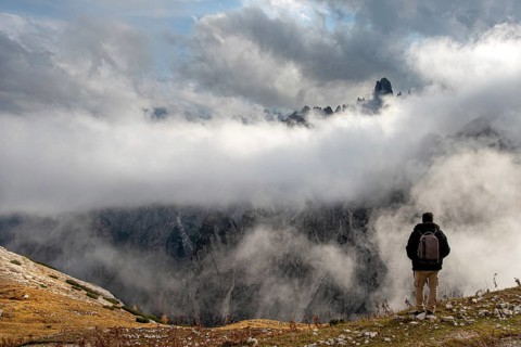 Man arms outstretched at sunrise enjoying landscape freedom and life. Tre cime di lavadero Italian