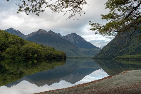 Tranquil lake Gunn in Fiordland National Park, landscape reflecting on the water surface, South