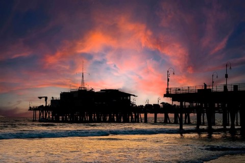 Silhouette of a roller coaster at sunset on a California coastline