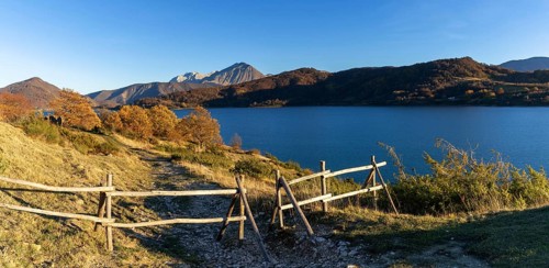 A wooden fence and hiking trail on the banks of Campotosto Lake in the mountains of Abruzzo in