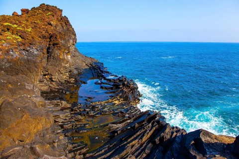 Small bay with azure water. Volcanic island of Madeira. Grottoes and rocks of the Atlantic coast.