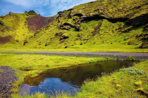 Picturesque basalt hills overgrown green grass and moss. On bottom of canyon many streams flow.