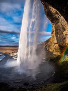Seljalandsfoss, a majestic and powerful waterfall in Iceland in a sunny spring day with a raibow