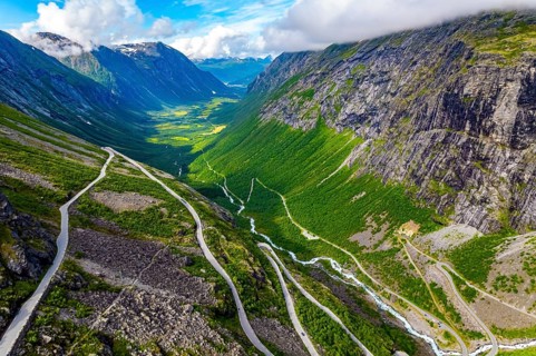 The serpentine road meanders on the green slopes of the canyon. Filming from a drone. Summer trip