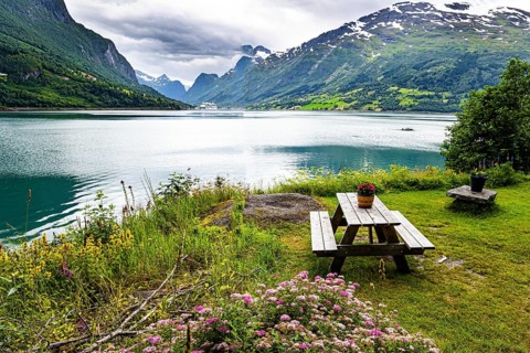 Wooden table and benches on the banks of the picturesque Lovatnet. Northern Europe in July. Summer