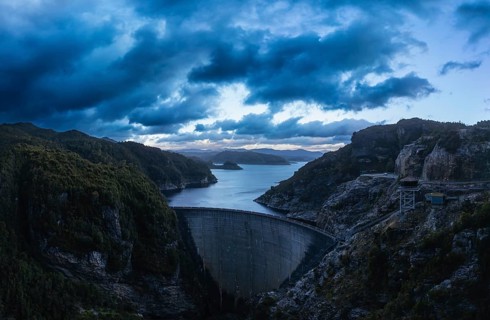 An aerial view of the Gordon Dam on a cool summer's day. It is a unique double curvature concrete