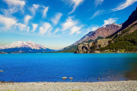 Huge lake with azure water rocky beach by the lake. Patagonia. Pampas surround snow-capped