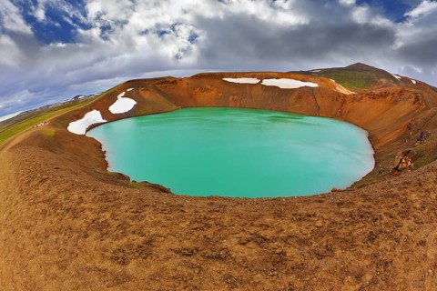 Krafla lake in the crater of an extinct volcano. Lake water bright green color. On the shores lie