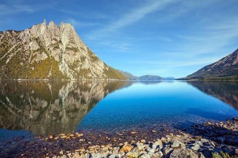 The concept of exotic and extreme tourism. The mirror water of the lake reflects sharp peaks and