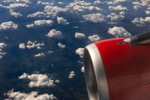 A colour landscape image looking out through airplane window showing land, cloud and sky