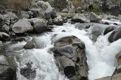 Whitewater rapids swirling around large rocks in a river, The Alcantara Park is located on the