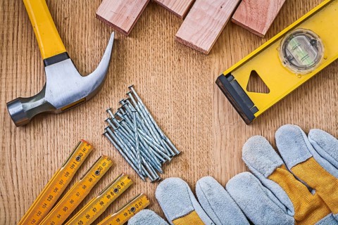 Set of tools claw hammer stack of nails safety gloves construction level wooden meter planks on