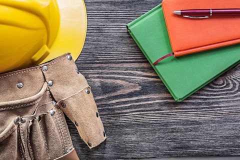 Collection of tool belt notepads pen building helmet on wooden board construction concept