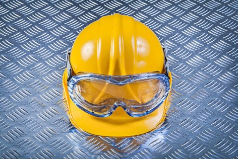 Safety glasses hard hat on grooved metal plate construction concept