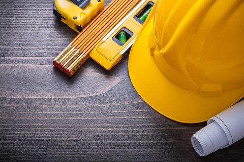 Tape-line blueprints construction level hard hat and wooden meter on vintage wood board maintenance