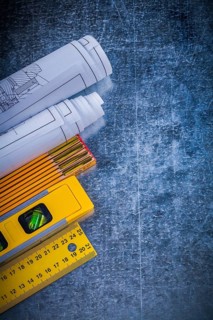Blueprints yellow ruler construction level and wooden meter on metallic scratched background