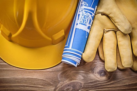 Blue blueprint hard hat protective gloves on wooden board construction concept