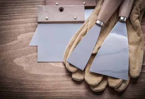 Two paint scrapers putty knifes working gloves