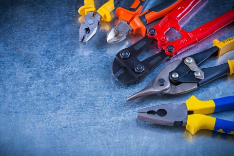 Set of bolt cutter tin snips cutting pliers gripping tongs on scratched vintage metallic surface