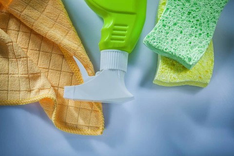 Plastic sprayer washing sponge cloth on white surface