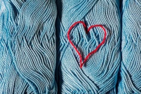 Knitted red heart on blue balls of yarn