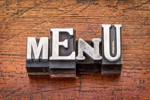 Menu word in vintage metal type printing blocks over grunge wood