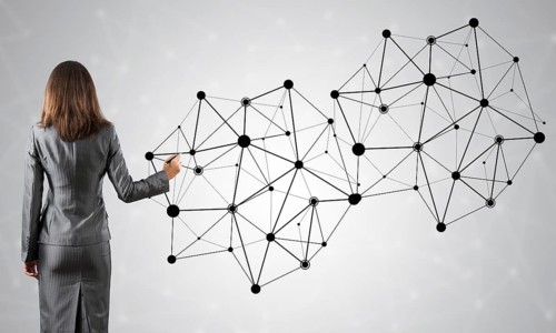 Businesswoman standing with back to camera and drawing with marker connection lines