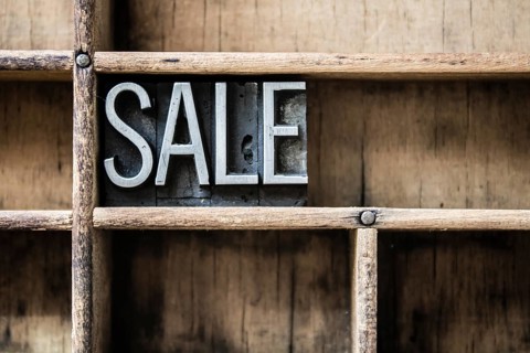 The word SALE written in vintage metal letterpress type sitting in a wooden drawer