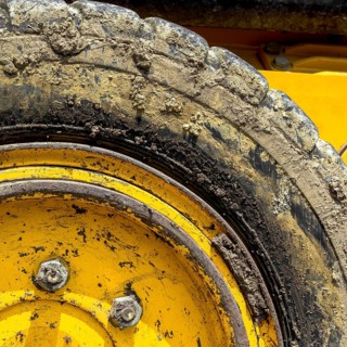 Extreme close up of tire bulldozer, yellow and covered with mud